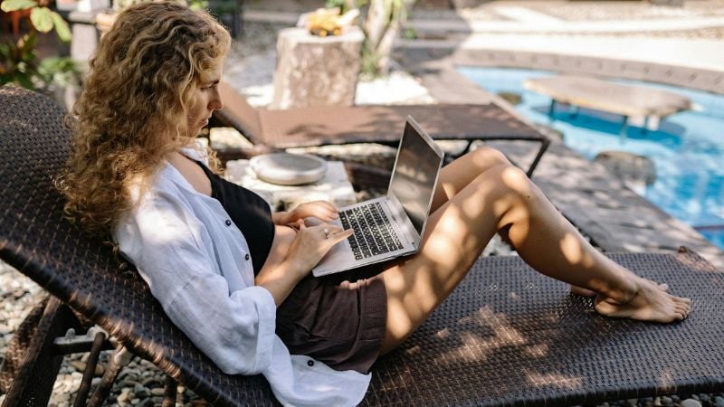 Woman working on laptop near pool